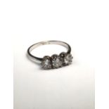 An unmarked platinum and diamond three stone diamond ring. centrally set with 5mm old brilliant