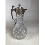An unmarked white metal mounted cut glass claret jug with dragon head handle, acorn finial and