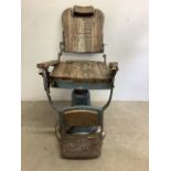 An early swivel action metal and wood barbers chair with original paintwork and metal footrest.