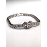 A platinum and diamond line bracelet set with central 5.5mm brilliant cut diamond on a line of 32