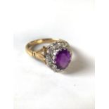 An 18ct gold amethyst and diamond dress ring. central oval free cut amethyst with a surround of