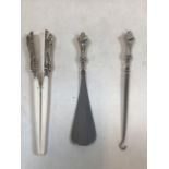 Three silver handled items including a button hook, a shoe horn and a glove stretcher