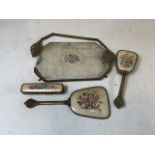 A four piece dressing set to include mirror, two brushes and a footed tray. (Tray in need of