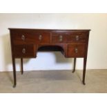 An Edwardian inlaid leather topped writing desk on metal castors. With four drawers and brass