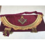 Masonic interest. Decorative pouch with gold banding and metal tassels on burgundy background.