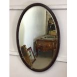 A mahogany framed oval bevelled mirror. W:60cm x H:90cm