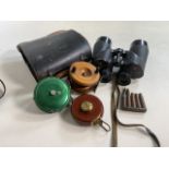 Two fishing reels also with a pair of binoculars, leather cased tape measure and some bullets.