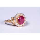 An unmarked precious yellow metal ruby and diamond dress ring. Central oval free cut ruby 2ct