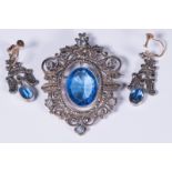 An unmarked white metal Victorian brooch and earring suite. Centrally set with large oval blue paste