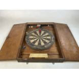A dart board with wooden case by Accudart. Plus five darts. W:52.5cm x D:9cm x H:77.5cm