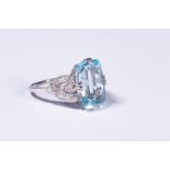 A platinum aquamarinbe and diamond dress ring. Central 8.5ct free cut aquamarine with single cut