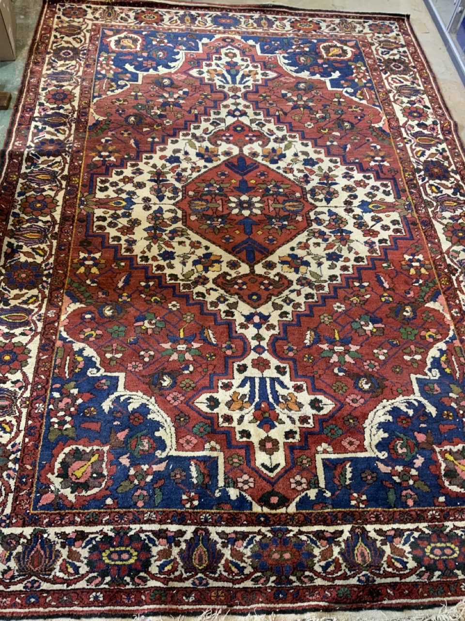 A red blue and cream ground carpet with large central medallion with wide cream floral border.