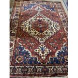 A red blue and cream ground carpet with large central medallion with wide cream floral border.