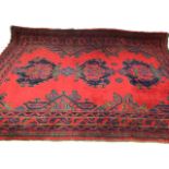 A red ground rug with three central green and blue medallions with four borders. W:210cm x H: