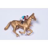 An unmarked precious yellow metal and enamel jockey brooch. 9.8g. W:3.8cm x H:3cm