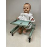 A Triang 1920s baby chair on ceramic castors with a Heinrich Handwereck doll