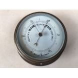 A brass aneroid barometer.