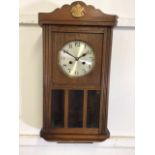 An oak cased wall clock with gilt painted flour de lis, with pendulum and key. W:31cm x D:18cm x H: