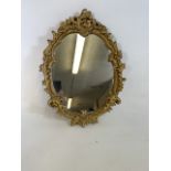 A gilt framed oval Rocco style mirror . W:51cm x H:64cm