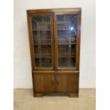 A C.1940s oak cabinet with glazed leaded doors to interior shelves with storage cupboard below. With