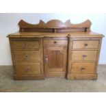 A large Victorian pine desk cabinet with central cupboard with drawer above, flanked by two banks of