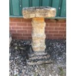 A three piece reconstituted stone bird bath on tiered plinth.