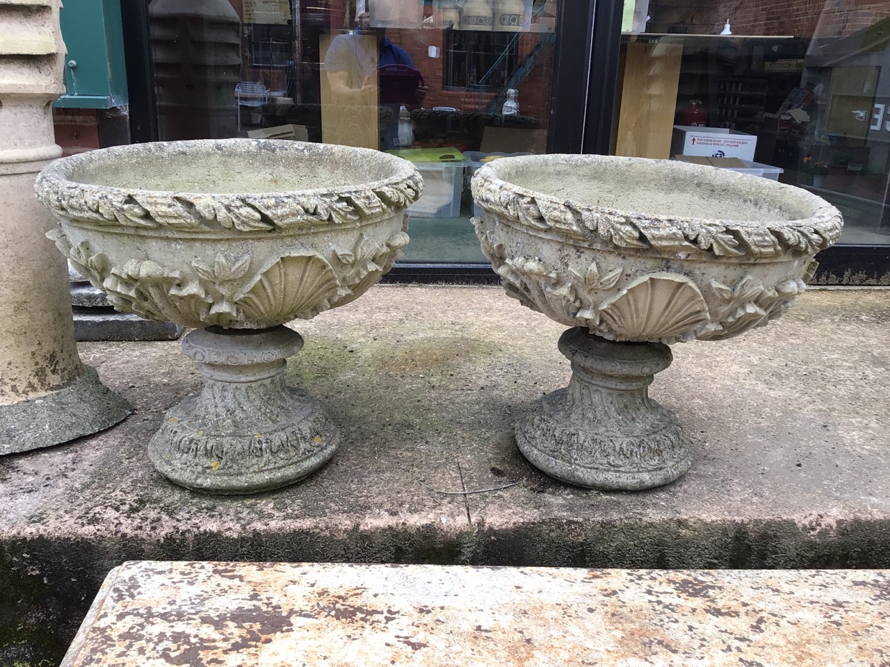 A pair of decorative circular reconstituted stone planters on separate plinths. W:53cm x D:53cm x