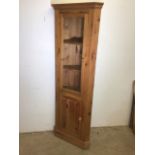 A modern pine corner cupboard with glazed door to two shaped shelves with lower cupboard also with