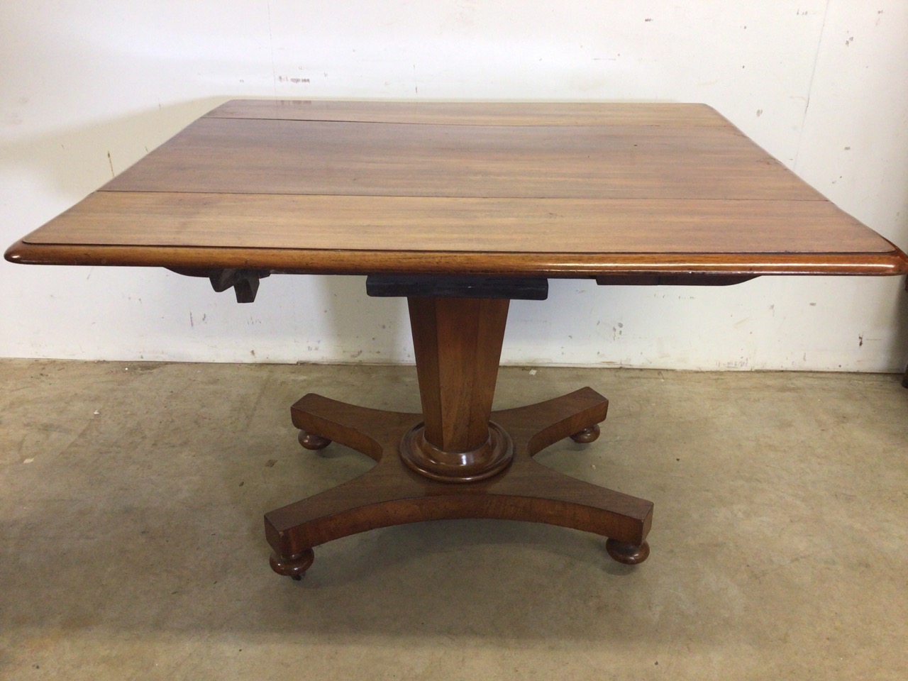 A Victorian Pembroke table with drop leaf sides, pedestal base with turned feet on metal castors.