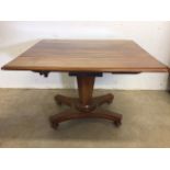 A Victorian Pembroke table with drop leaf sides, pedestal base with turned feet on metal castors.