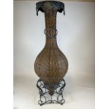 A large wicker conservatory vase in stand with metal hoop handles and decorative metal top. W:24cm x