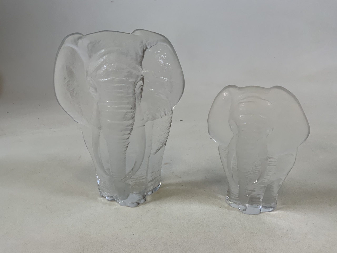 Two Mats Jonasson Swedish frosted glass elephant paperweights signed. The largest 20cm high x 16cm