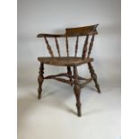 A Victorian smokers bow arm chair with curved top rail and turned spindles with saddle shaped seat