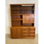 A McIntosh teak mid century two piece glazed wall unit, with smoked glass sliding doors to shelf