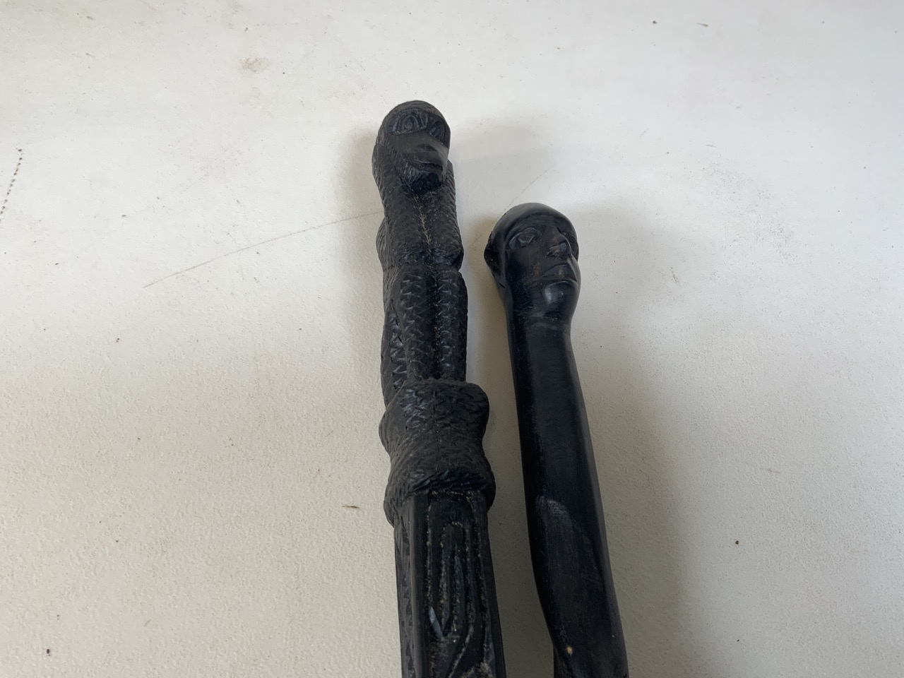 Two carved walking sticks - one with a carved monkey pommel and the other with a carved head .