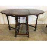 An oak oval gate leg table. W:137cm x D:90cm x H:77cm W:50cm x D:90cm x H:77cm