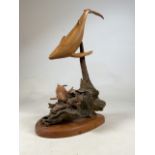 A carved wooden whale sculpture on a rounded plinth. H:63cm