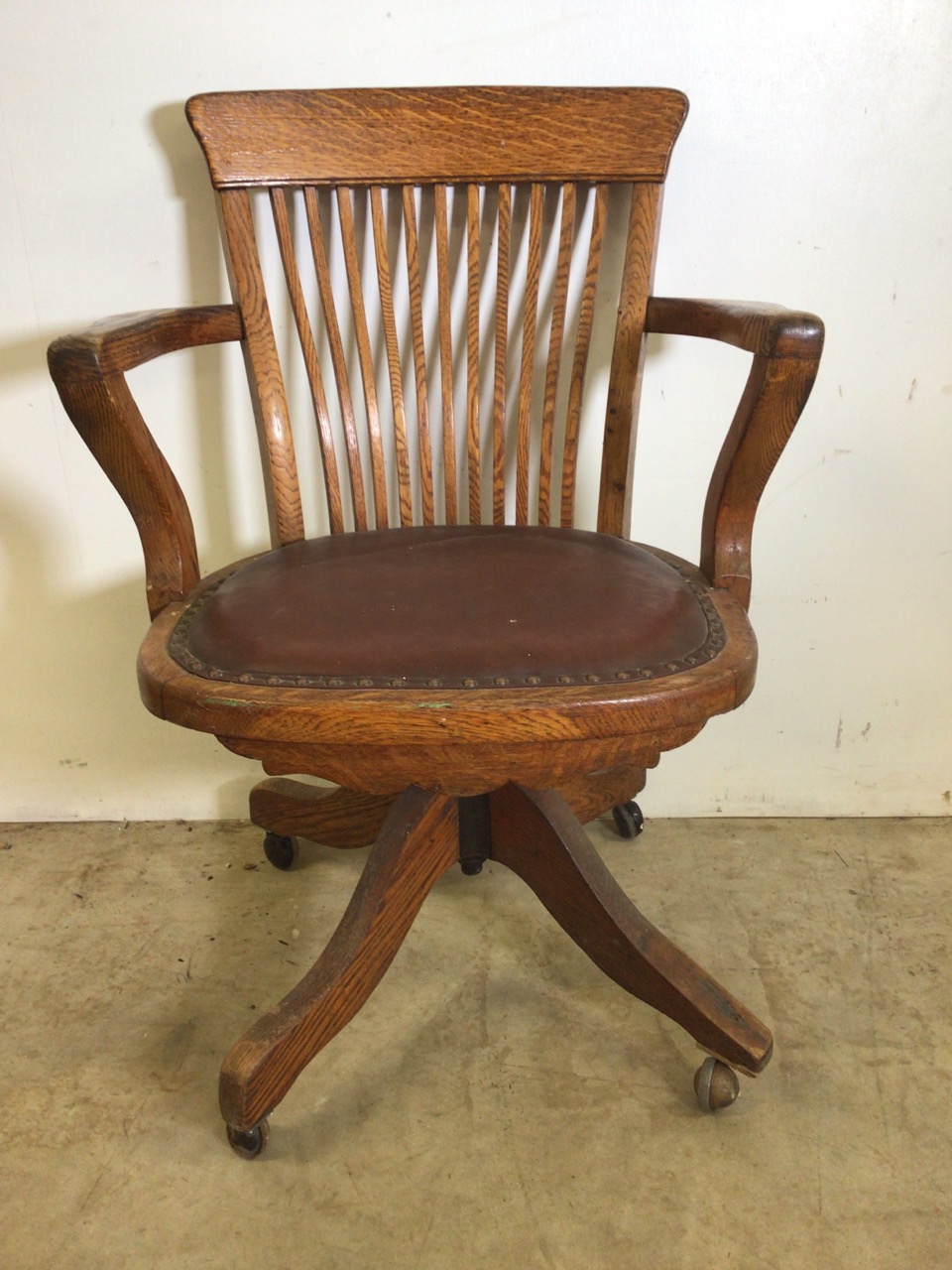 An early 20th century oak captains chair with tilt and swivel action, metal mechanics to base.