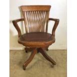 An early 20th century oak captains chair with tilt and swivel action, metal mechanics to base.