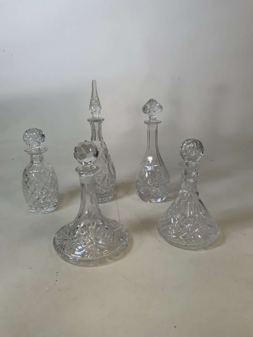 Two glass ships decanters together with three others