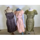 A trio of 1950s dresses - including a shoe string strap polka dot dress, an orange figured fit and