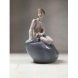 A Royal Copenhagen Porcelain Figure of 'The Little Mermaid', seated on a rock, printed and painted