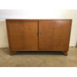 A mid century teak cupboard with sliding doors to interior shelves and pull out drawer. W:137cm