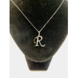 White gold R initial pendant on necklace chain, decorated with inset stones.