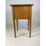 A mid century oak sewing box with chamfered legs and top, with lift up lid to compartments and