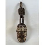 A 19th century African tribal mask with carved stalk figure. H:72cm