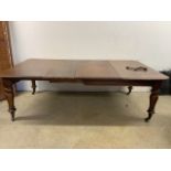 A Victorian mahogany extending table with two extra leaves on turned legs with large castors, with