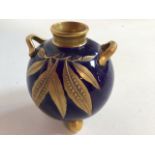 A Royal Worcester round vase on three ball feet with handles in colbalt and gold decorated with