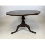 A low oak tilt top table on tripod base. W:76cm x D:76cm x H:51cm