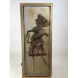 An Eastern articulated puppet mounted on a framed board